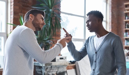 Two men looking at eachother in a workplace environment with one pointing his finger