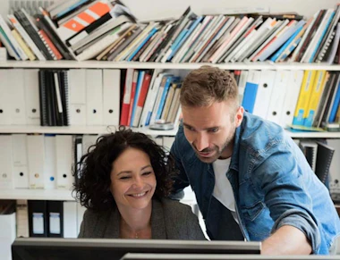 A pair of co-workers looking at a screen.