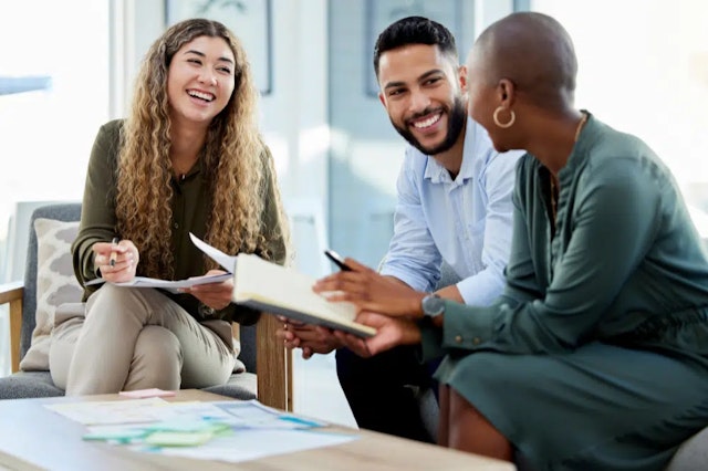 three people sitting around a coffee table smiling