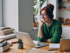A woman with a headset looks at her laptop