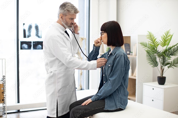 a doctor asking a patient to cough so he can listen to her chest