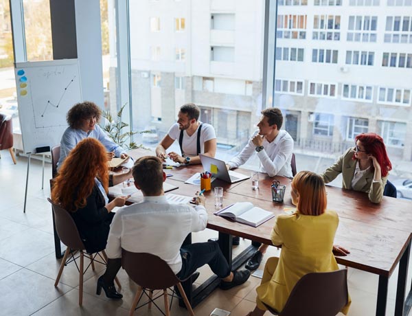 A group of workers sit at a table and look at a presentation.