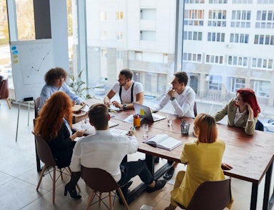 A group of workers sit at a table and look at a presentation.