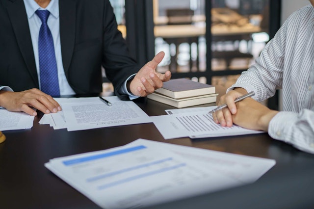 two men at a desk with paperwork