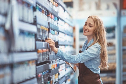 a woman in an apron dressing a shop shelf