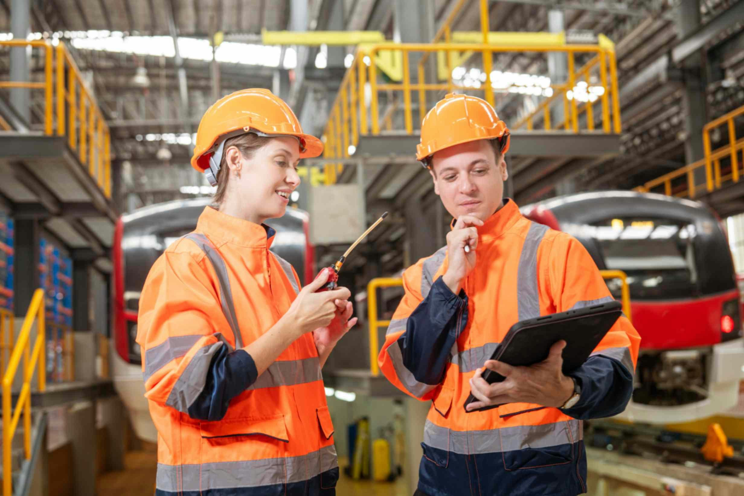 two workers in ppe in a warehouse looking at a clipboard