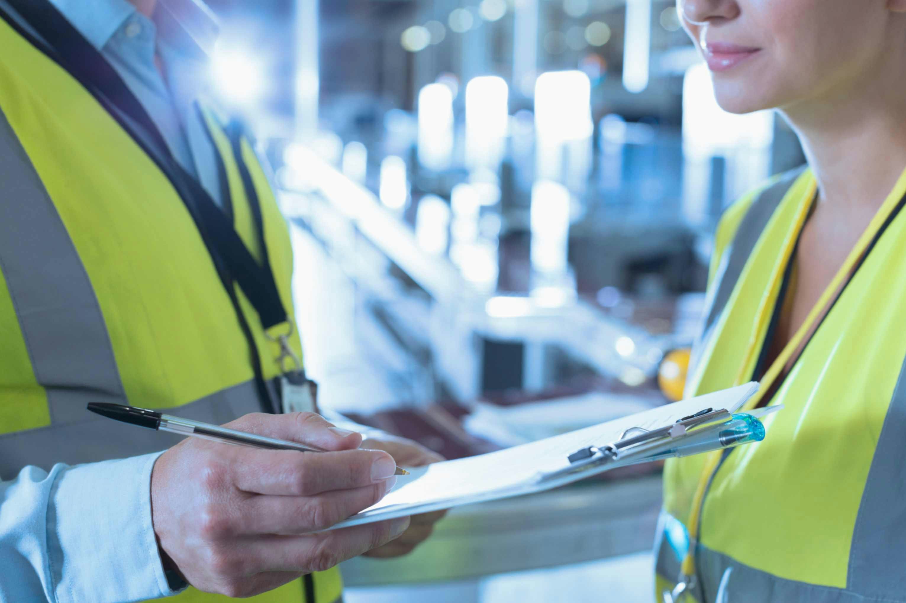 two people in ppe holding a clipboard