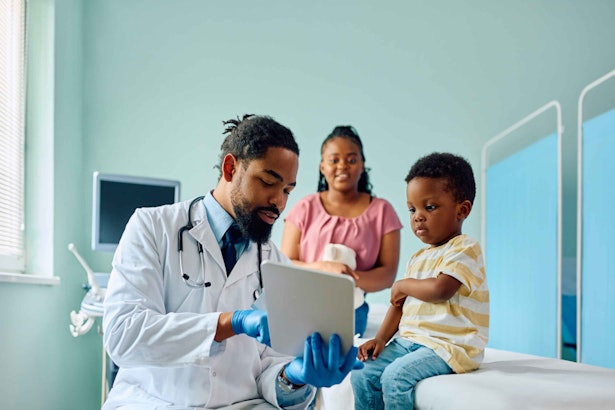 a male doctor talking to a child and his mother