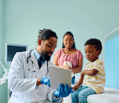 a male doctor talking to a child and his mother
