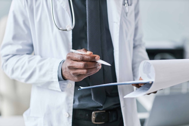 a man in medical uniform holding a clipboard and pen