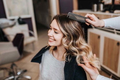 a woman smiling as someone combs her hair
