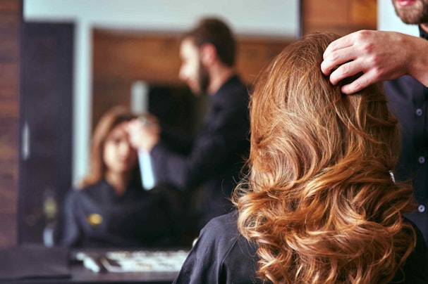 A woman looking at her hair in a mirror in a salon