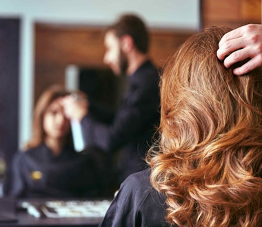 A woman looking at her hair in a mirror in a salon
