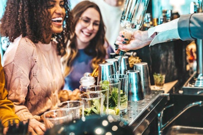 two women laughing as their drinks are poured