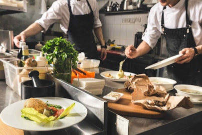 Two chefs dishing a meal onto a plate