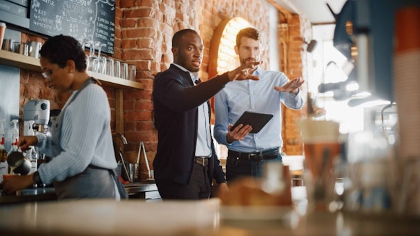 two men pointing in a restaurant with a tablet