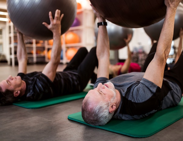 two men lying down holding a fitness sphere
