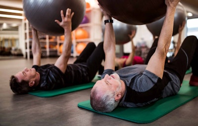 two men lying down holding a fitness sphere