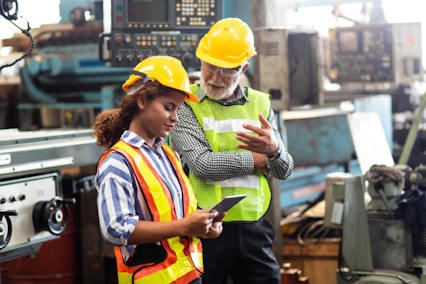 a man in woman in hard hats around machinery