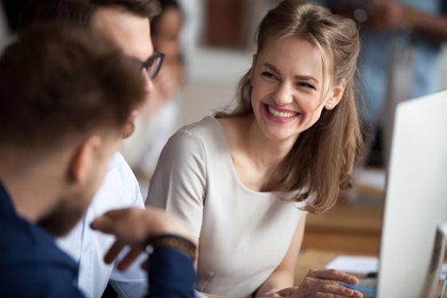 a woman smiling during a conversation with two men