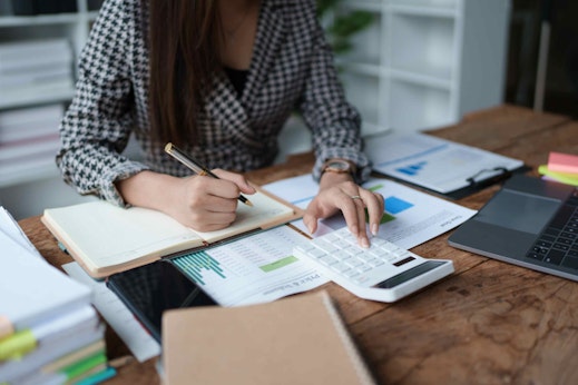 A woman typing into a calculator at a desk