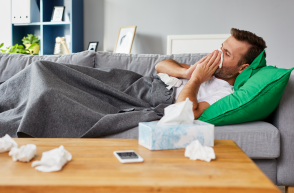 ill person lying on sofa blowing nose