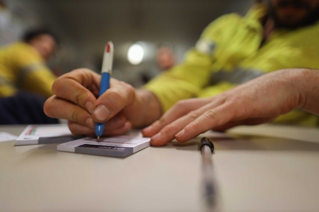 a person in high-vis writing on a notepad