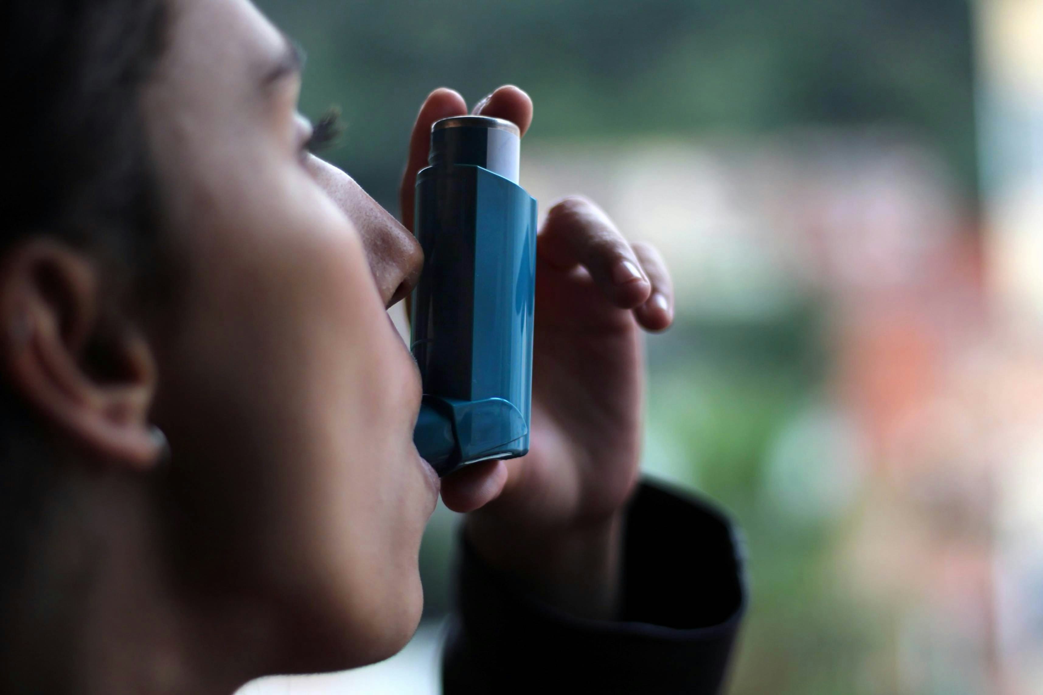young girl using blue asthma inhaler to prevent an asthma attack