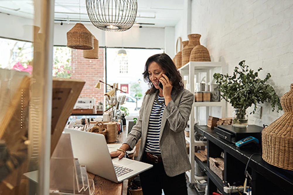 person using laptop and phone in shop
