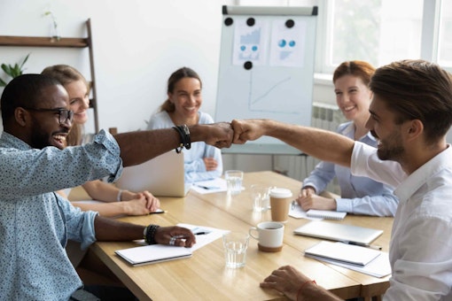 employees fist bumping eachother around a table