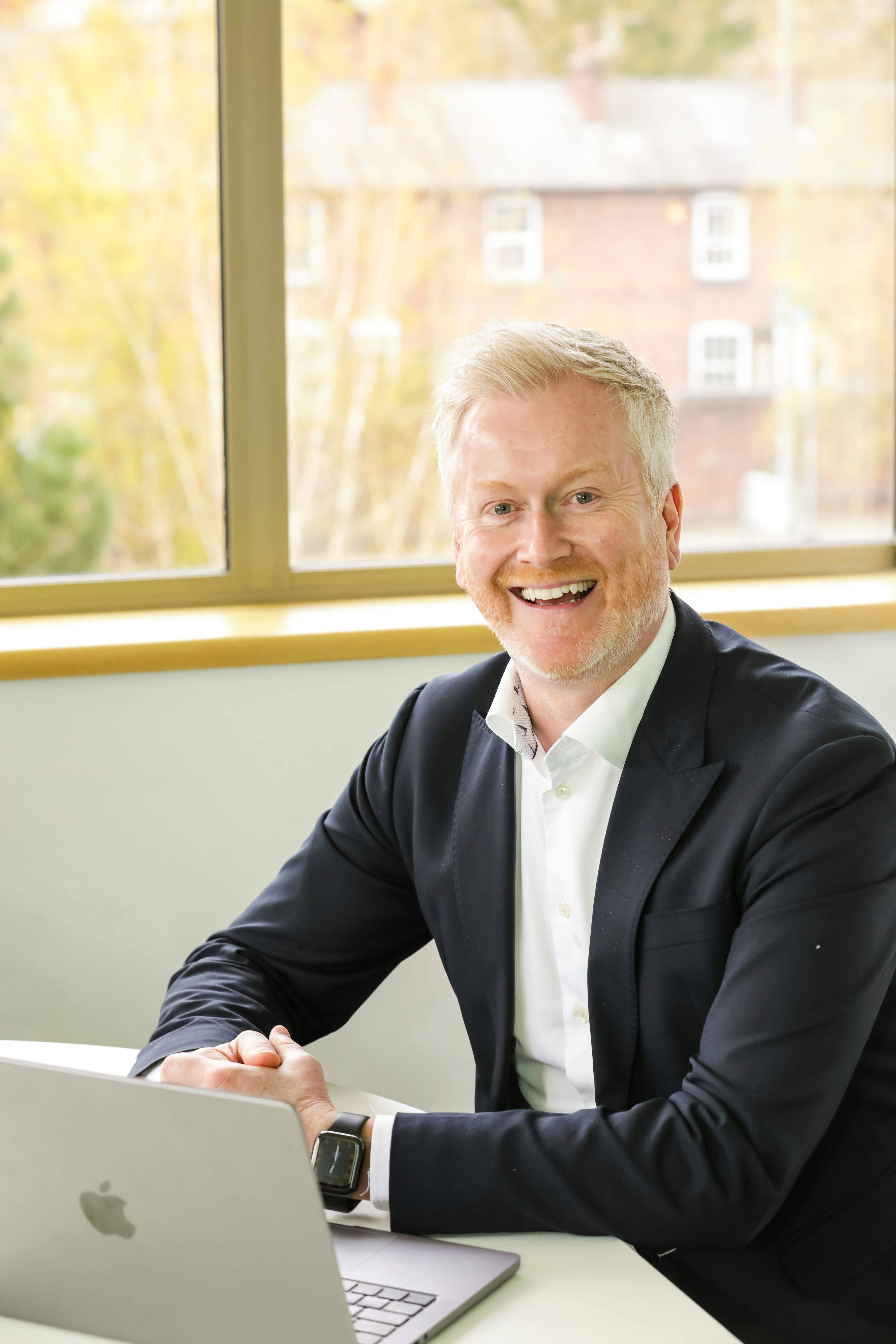 A smiling man next to an open laptop.