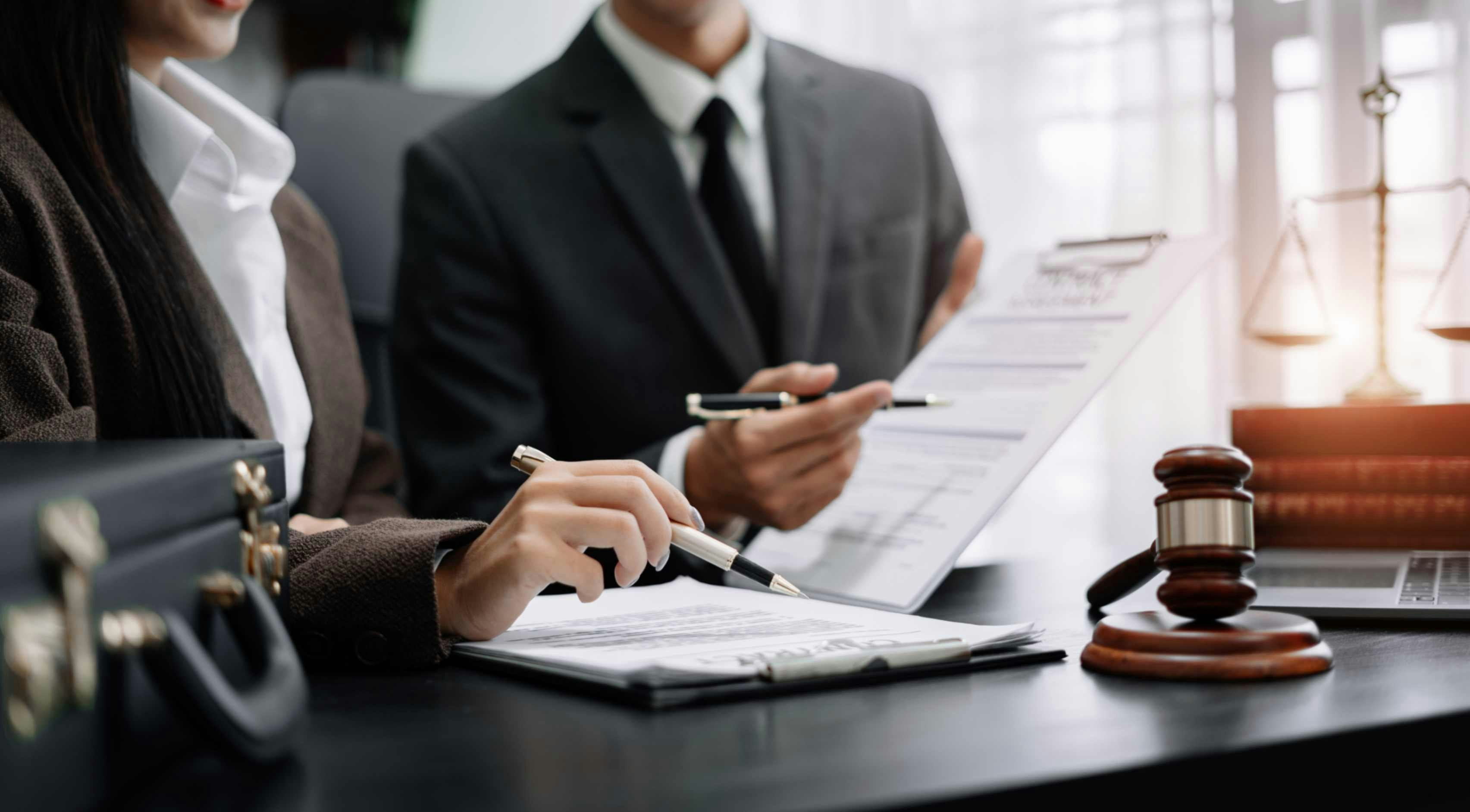two people with pens in suits pointing at a document