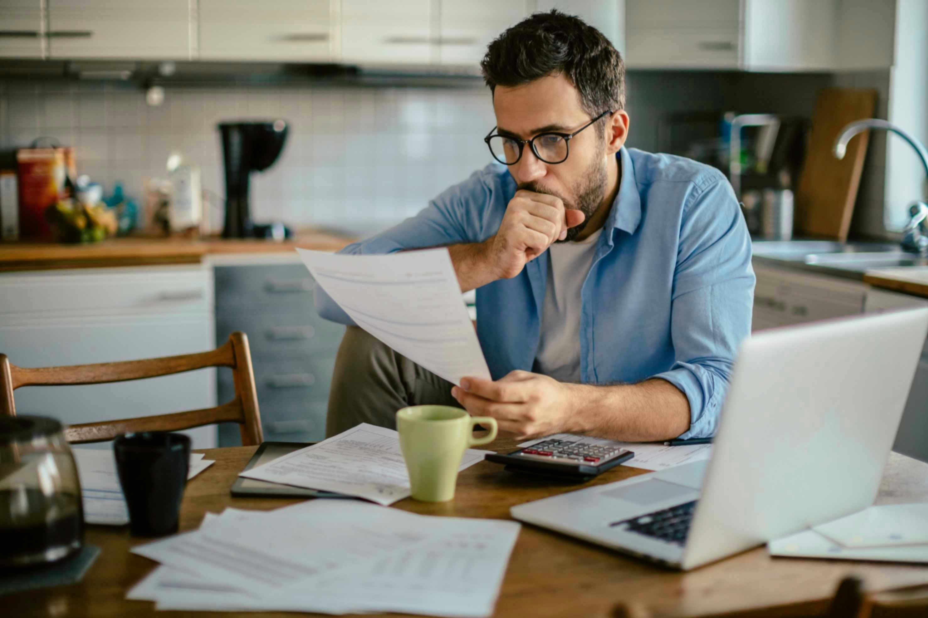 A man looking at a document at a kitchen table