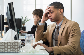 employee sat at desk surrounded by tissues