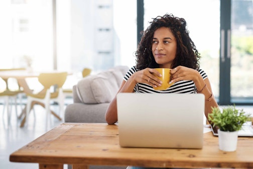 A woman at her laptop and desk with a mug