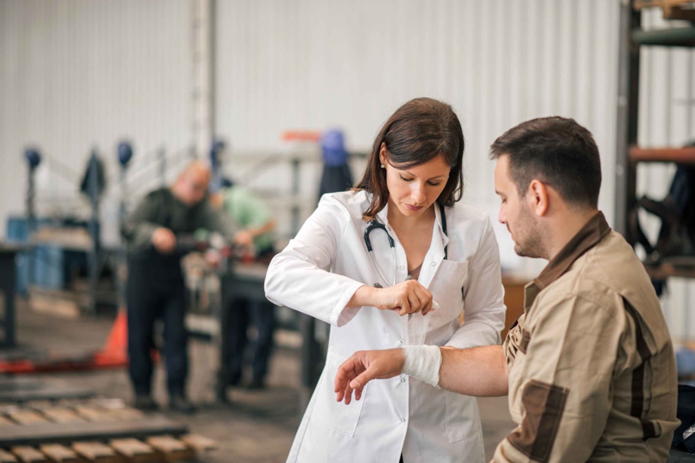 a doctor examining another worker in a warehouse