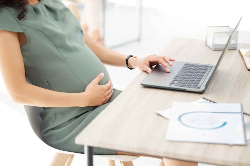 a pregnant woman sat at a desk