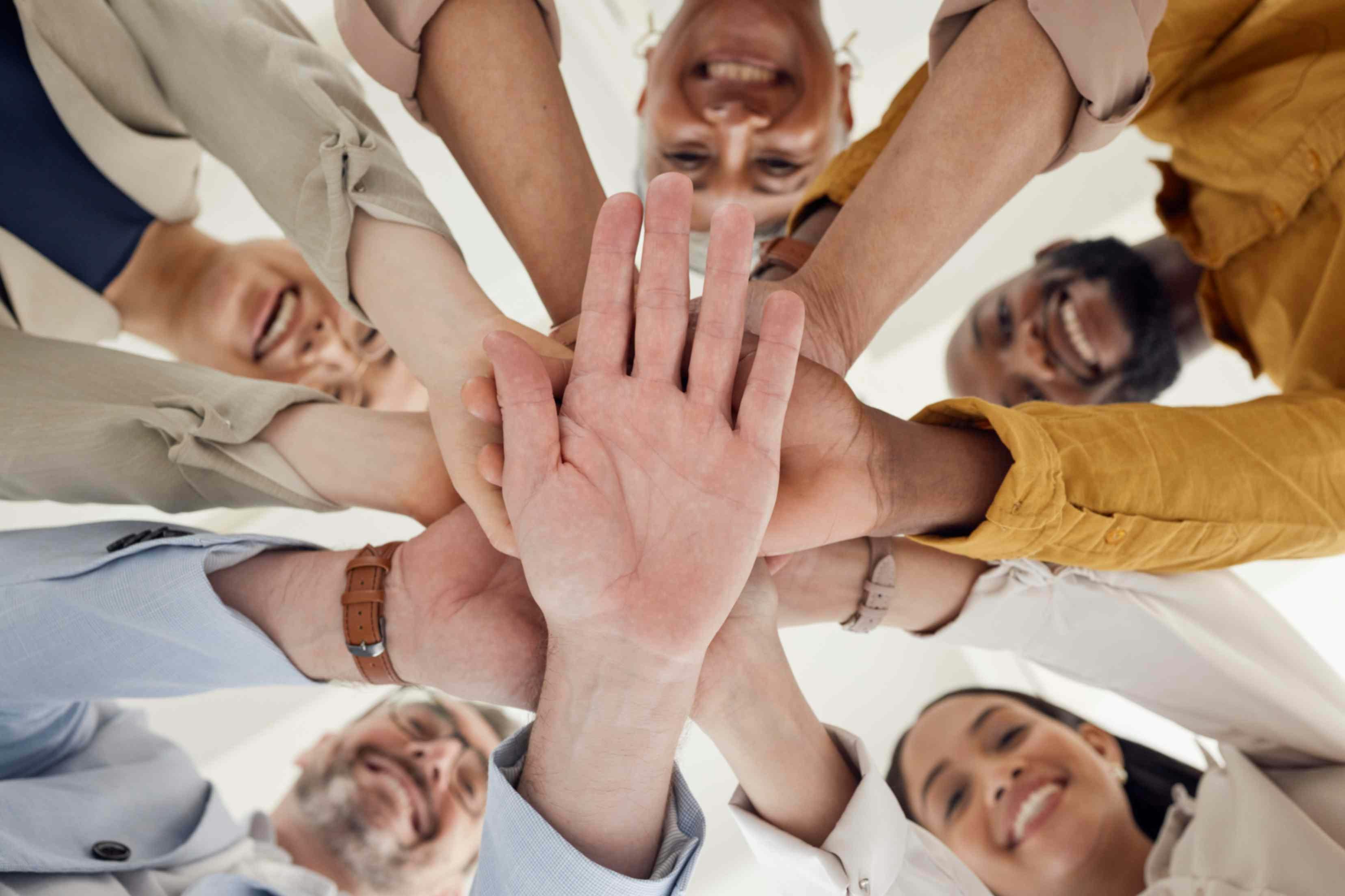 A group of people with hands in the middle smiling