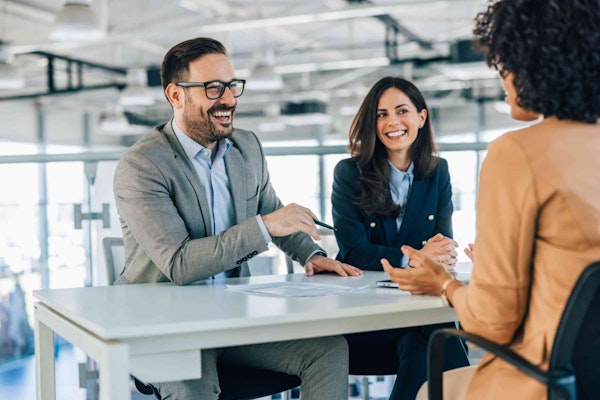 three people at a desk smiling