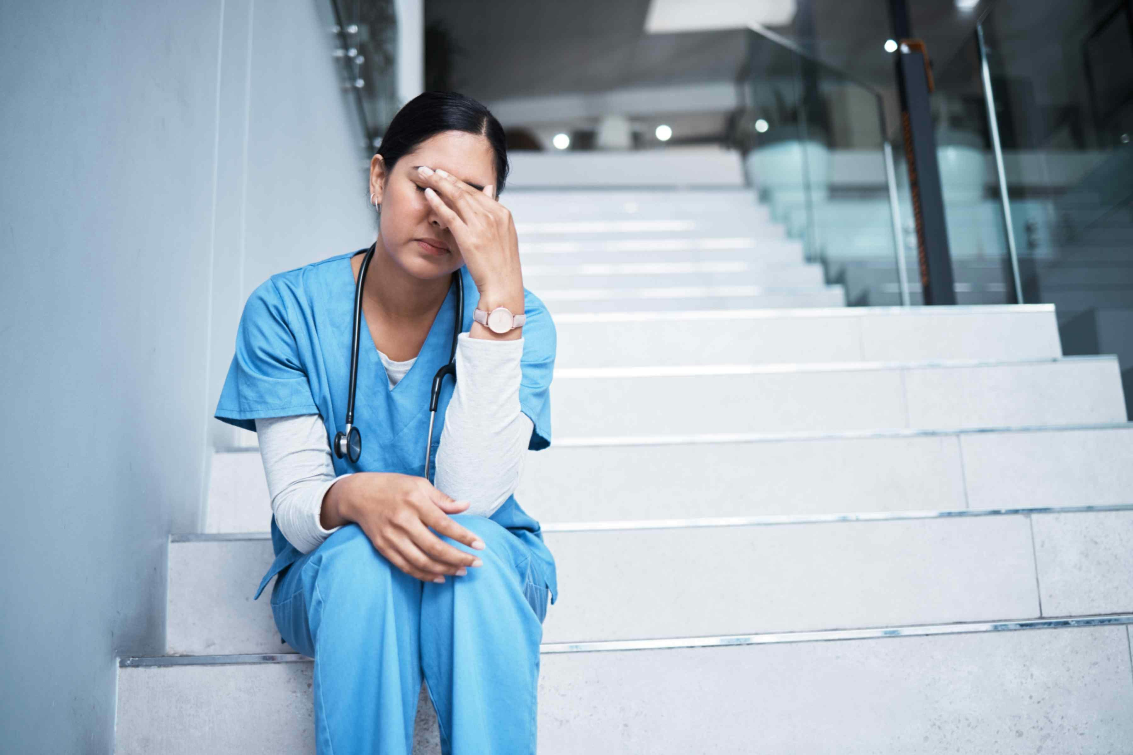 a nurse sat on the stairs with her head in her hands