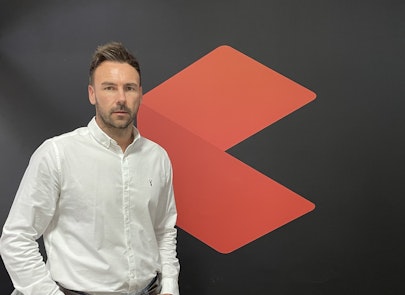 A man in a shirt standing against a wall.