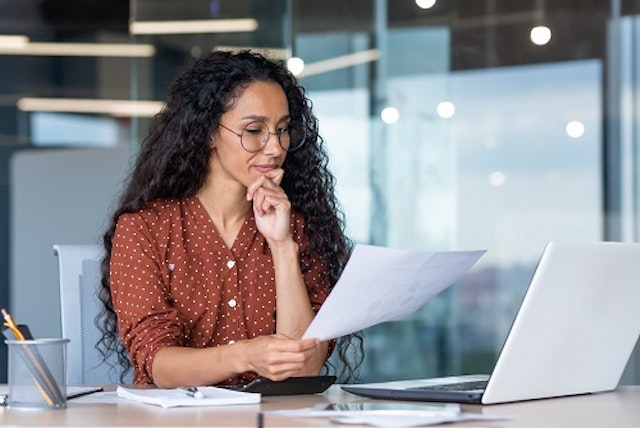 A women looking at a document whilst using a computer