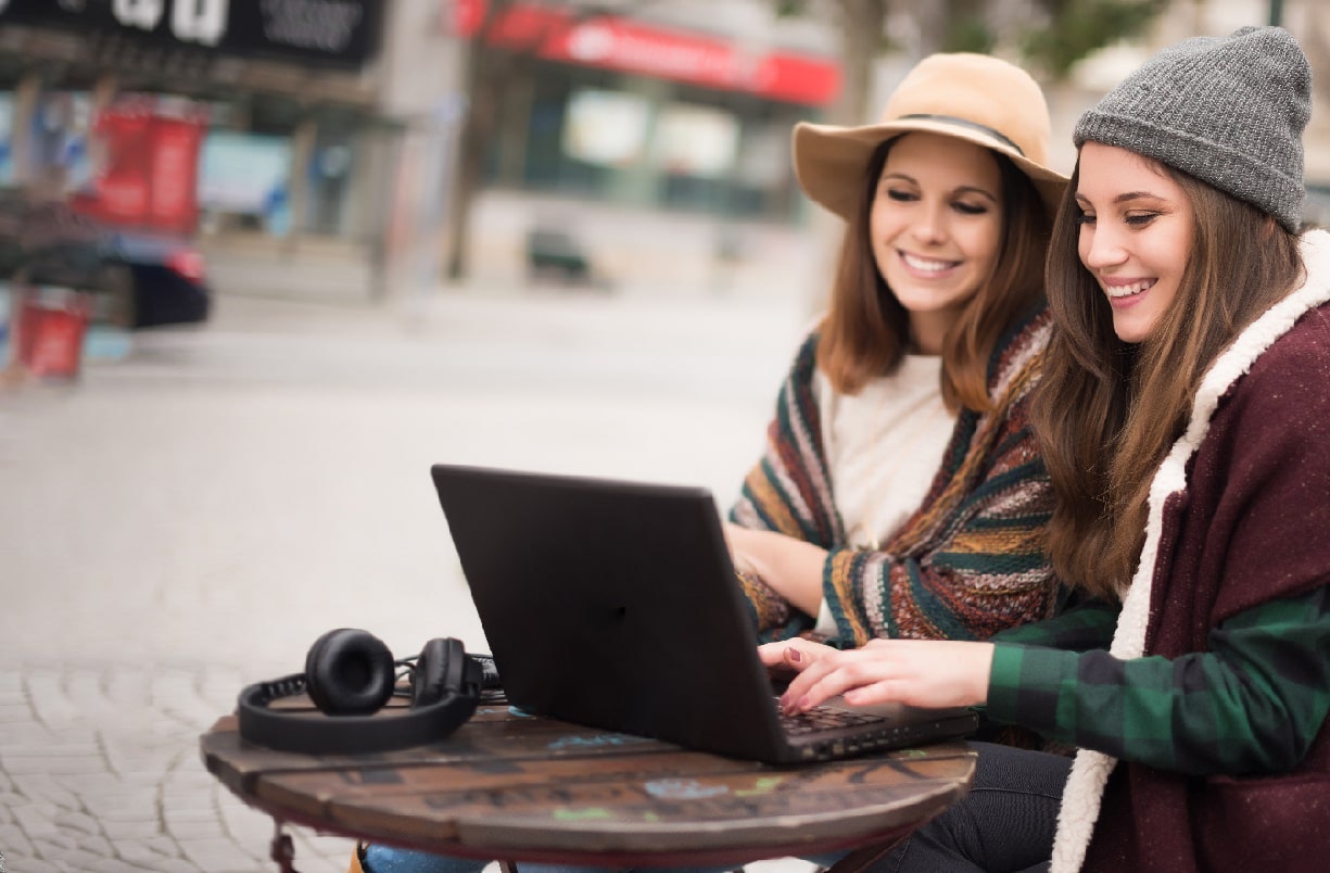 two women looking at laptop outside