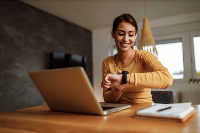 a woman sat at a desk checking her watch