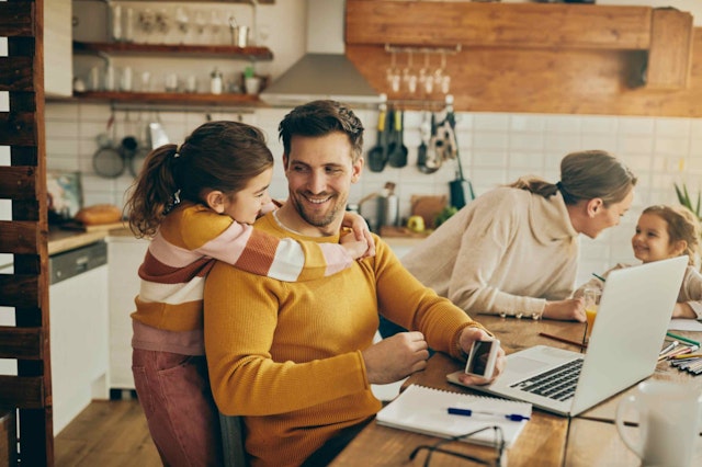 a man with a child laughing at his laptop