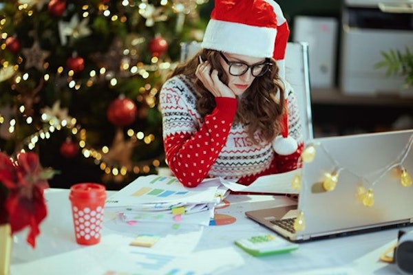 A boss wearing a Christmas jumper and Santa hat, focusing on their laptop