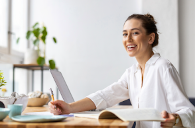 woman sat at desk with notebook and pencil