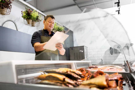 a man standing in front of meat with a clipboard