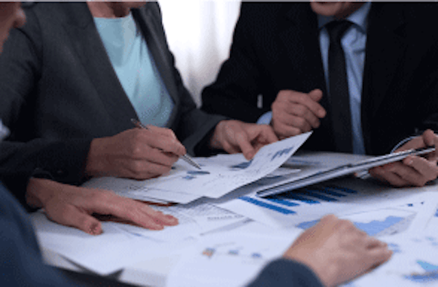 people in suits looking at spreadsheets