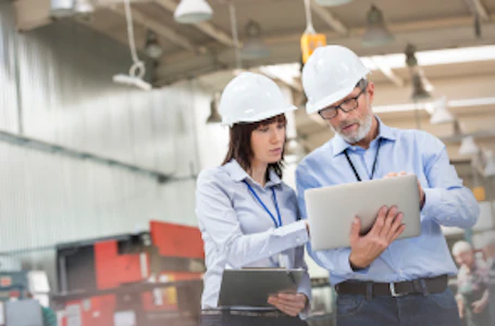 two employees in hard hats with clipboard